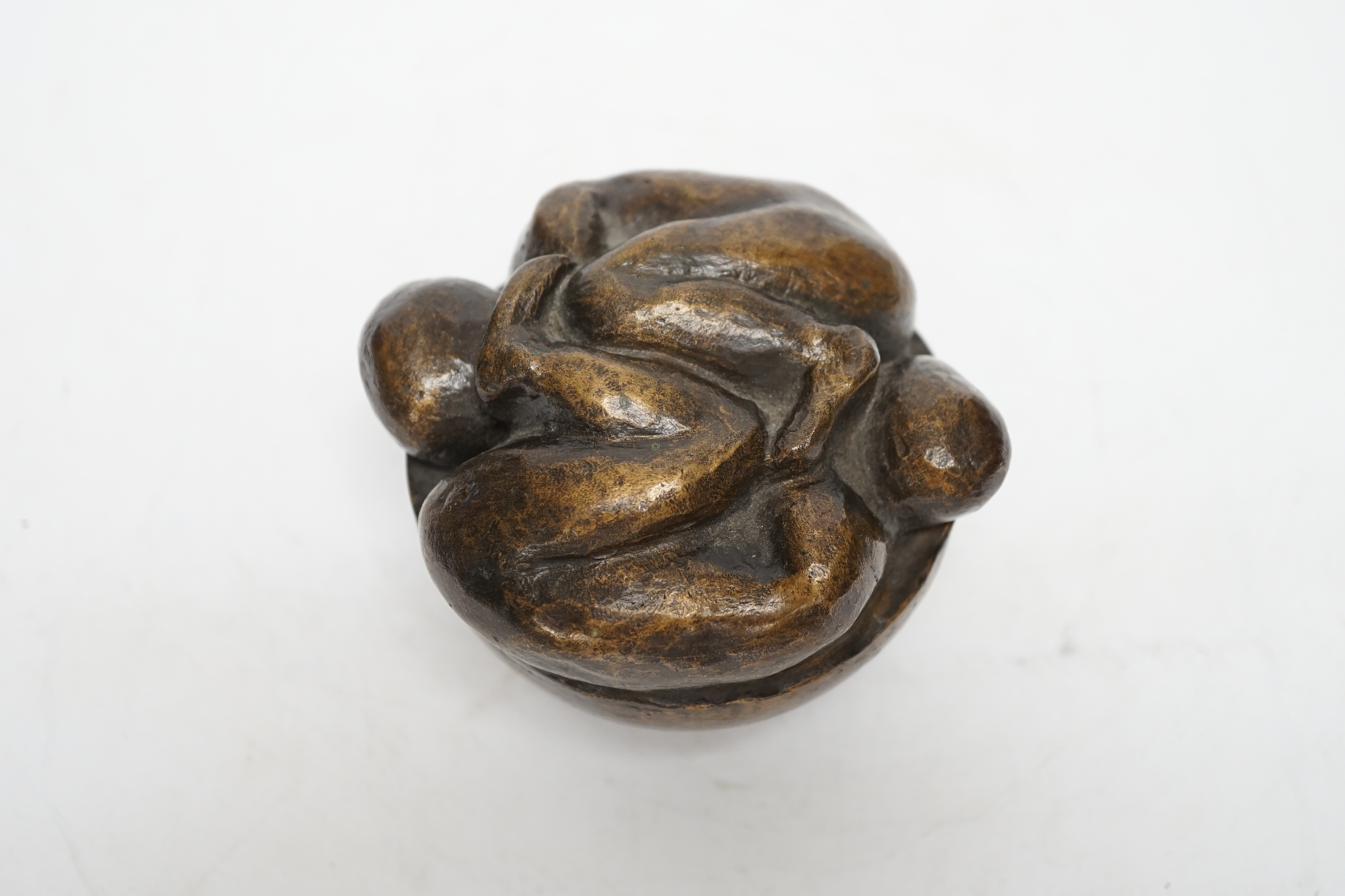 A squat bronze paper weight, the top of two intertwined figures, 8cm high